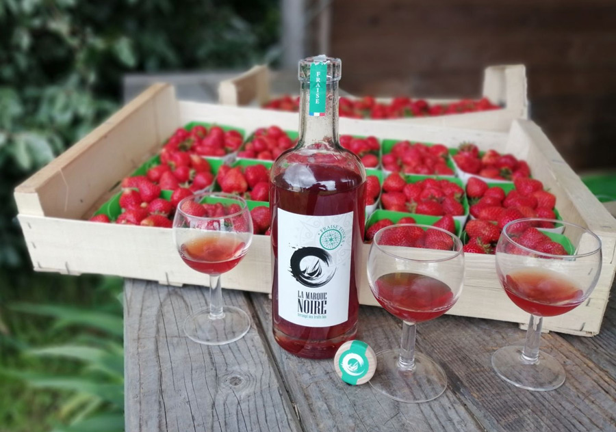 une cagette de fraises, une bouteille et trois verres servis de rhum arrangé à la fraise