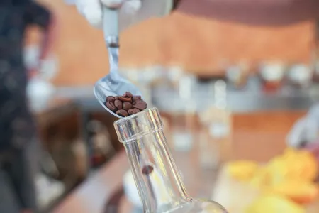 des grains de café sont versés dans une bouteille avec une cuillère à soupe